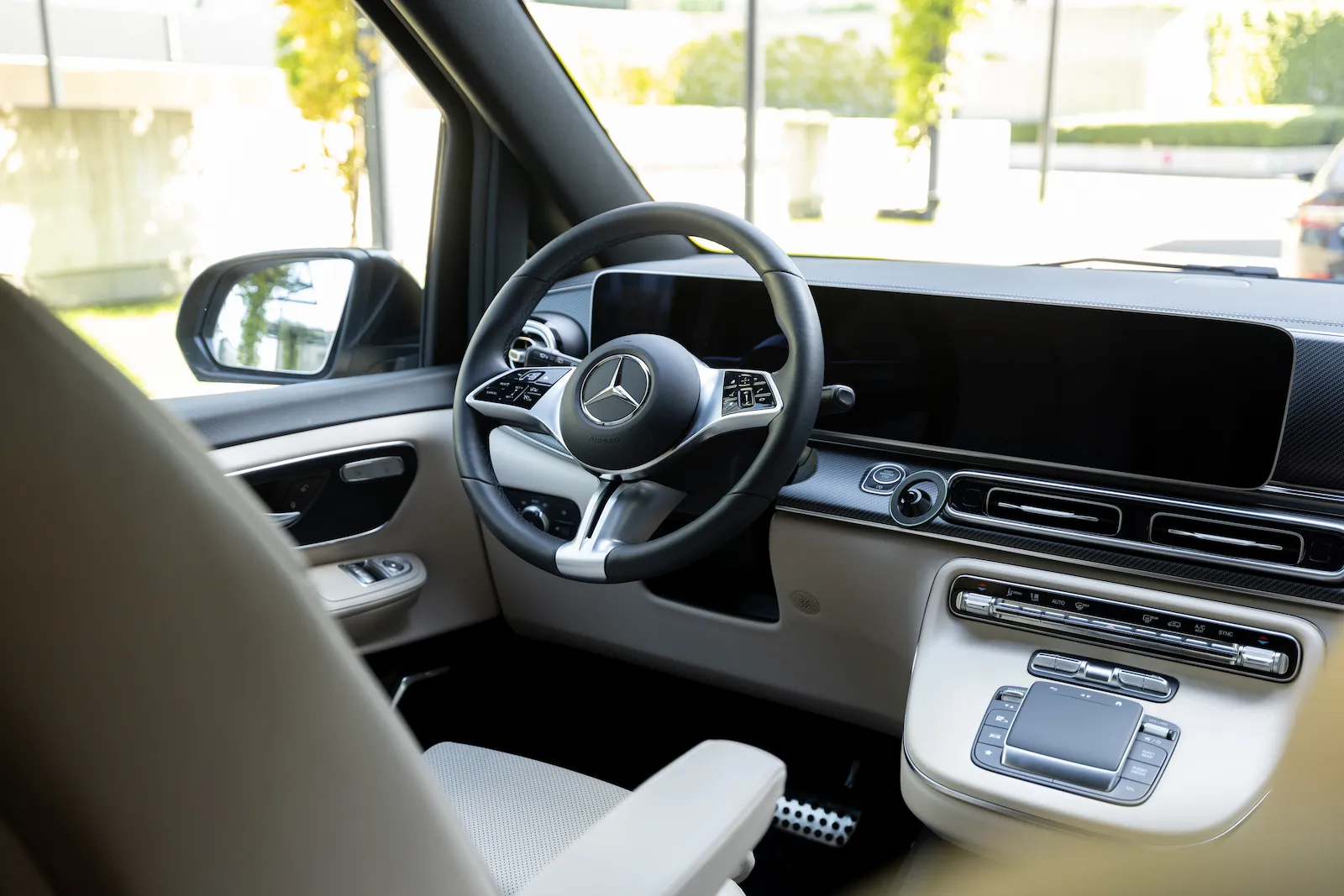 Mercedes Vito front inside view showcasing a luxurious dashboard and steering wheel, parked with a scenic outdoor background.