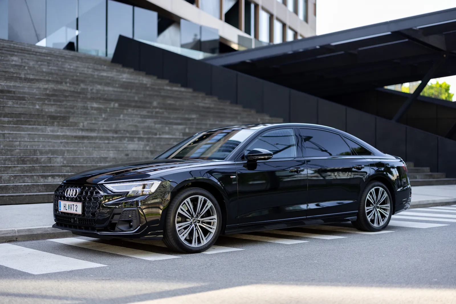 Elegante schwarze Audi A8 Class Limousine, geparkt vor modernen Stufen, ideal für luxuriösen Komfort.