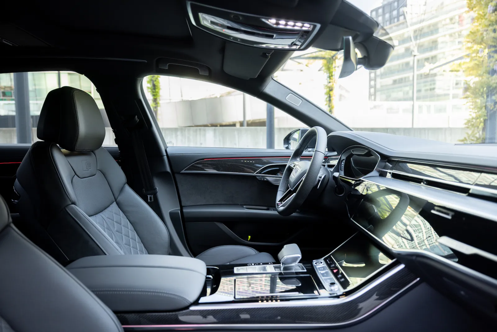 Moderne Audi-A8-Long-Innenansicht mit luxuriösen Ledersitzen und hochwertigem Armaturenbrett, geparkt vor einem urbanen Gebäude.