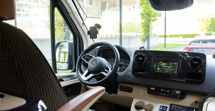 Der MB Sprinter VIP Front Inside View zeigt das luxuriöse Innere mit Lenkrad, Armaturenbrett und moderner Technologie, ideal für gehobene Reisemobile.